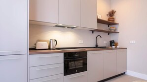 Una cucina moderna con mobili bianchi, forno integrato e macchina da caffè.