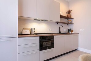 Eine moderne Küche mit weißen Schränken, einem Einbauofen und einer Kaffeemaschine.