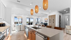 A modern kitchen with a large island, wooden cabinets, and pendant lighting. - Saylor's Delight: Beachfront NEW BUILD, Sugar Sands Mexico Beach, Private Pool & (Mexico Beach)