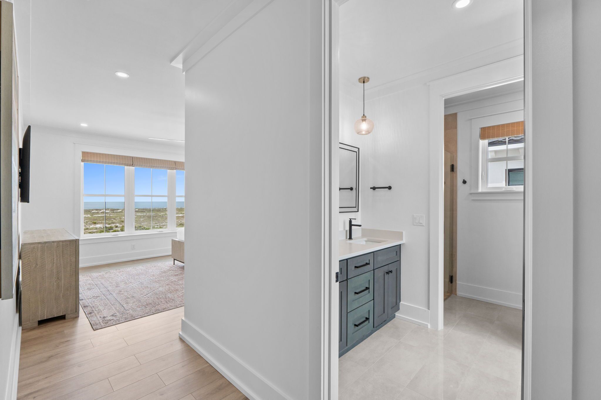 A modern interior with a kitchen area featuring grey cabinets, a countertop, and a hanging light fixture.