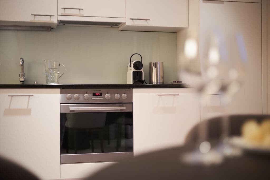 A modern kitchen with a built-in oven, a coffee maker, and a kettle on the countertop.
