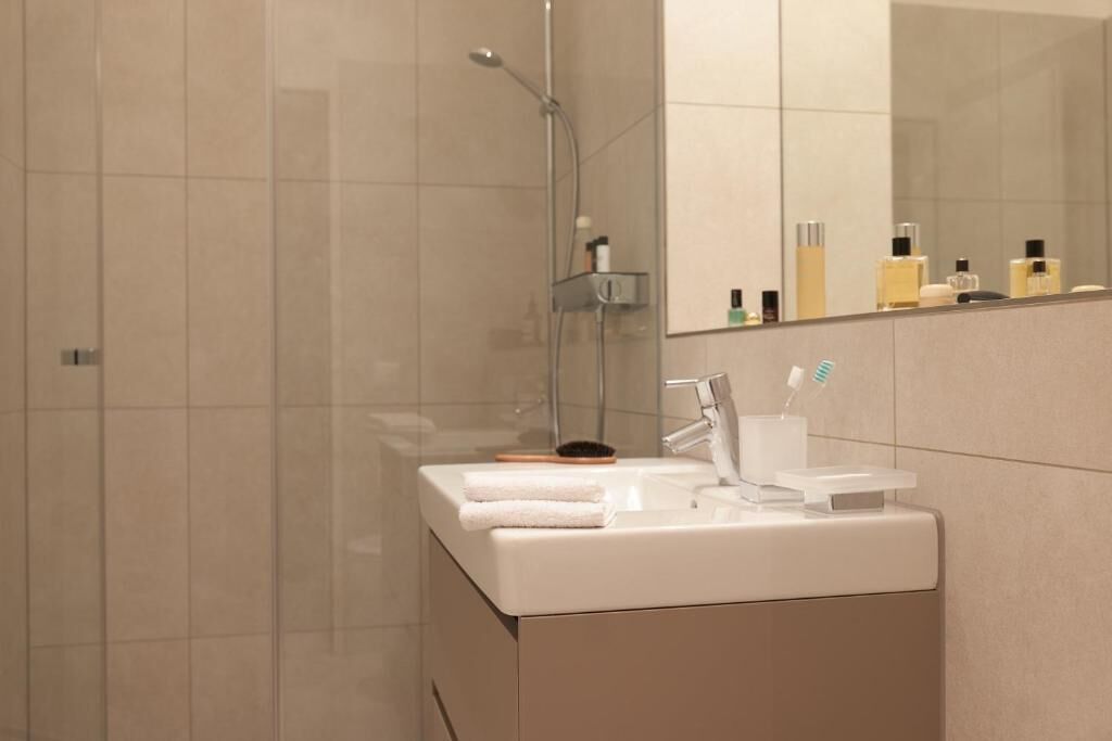 A modern bathroom with a shower, a sink with a mirror, and toiletries.