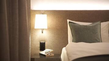 Une chambre d’hôtel avec un lit bien fait, une table de chevet avec une lampe et un téléphone fixé au mur.