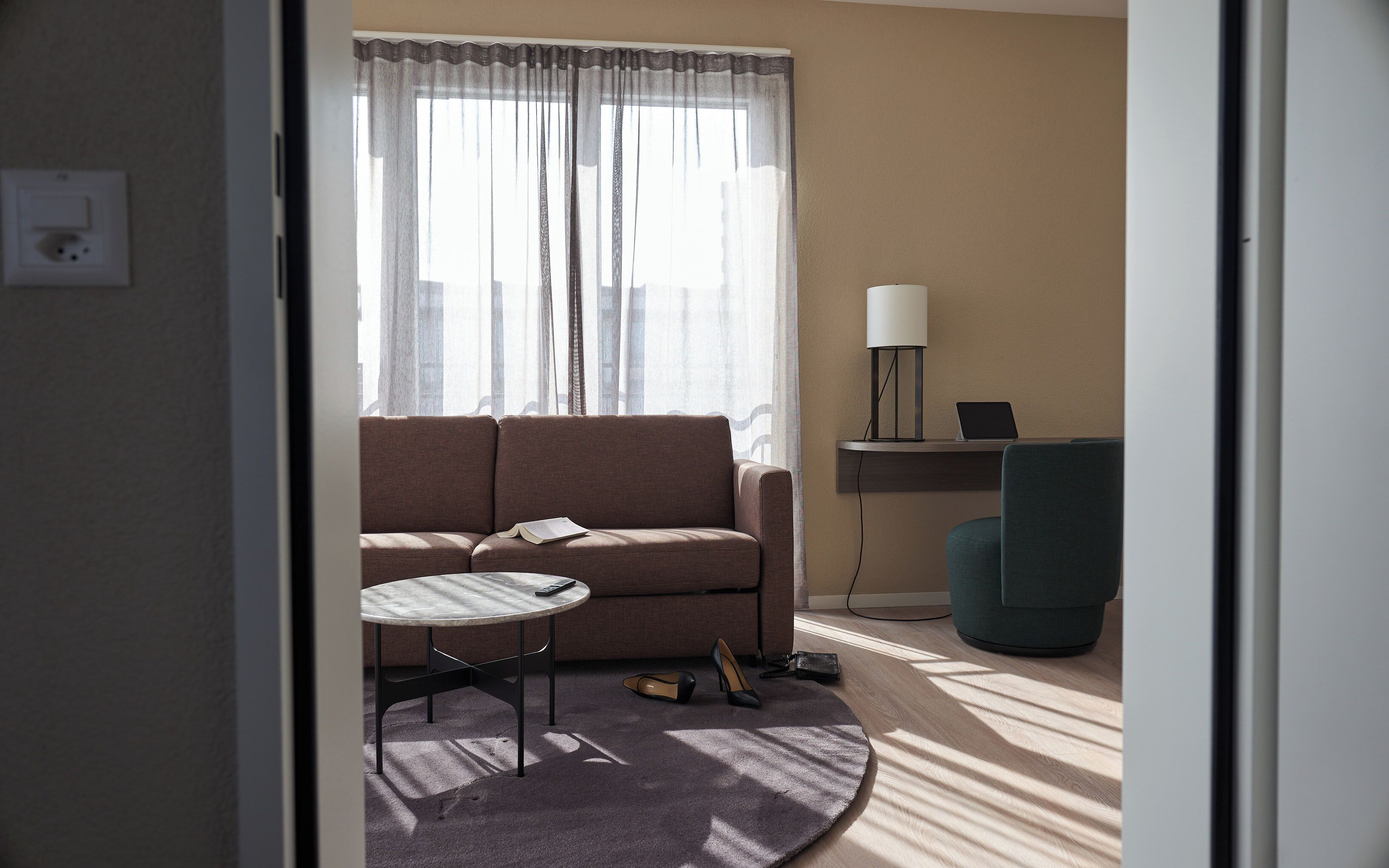 Ein Wohnzimmer mit einer Couch, einem kleinen runden Tisch, einer Lampe und einem Sessel.