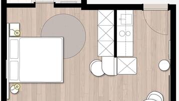 A floor plan of a hotel room with a bed, a seating area with a table and chairs, a small kitchen area, and a bathroom.