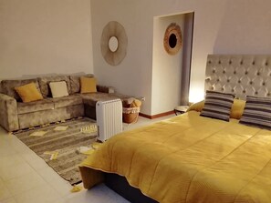 Ein Schlafzimmer mit einem Bett, einer Couch, einem Heizkörper und einem an der Wand befestigten Spiegel.