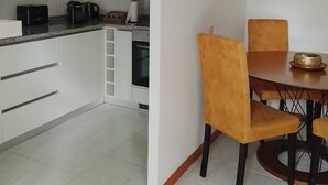 Eine moderne Küche mit weißen Schränken, einem Esstisch mit Stühlen und einer Kaffeemaschine.