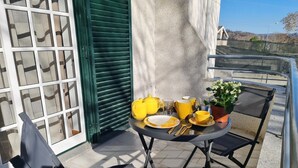 Ein kleiner Tisch im Freien mit gelbem Geschirr, einem Blumentopf und einem Stuhl auf einem Balkon.