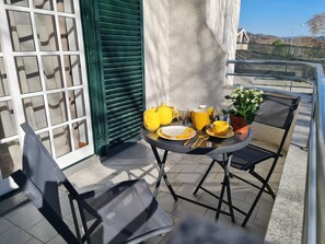 Ein kleiner Tisch im Freien mit gelbem Geschirr, einem Blumentopf und einem Stuhl auf einem Balkon.