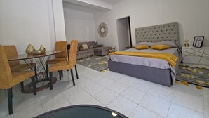 Ein Schlafzimmer mit einem Bett, einem Sofa, einem Esstisch mit Stühlen und einem kleinen Tisch mit Dekoration.