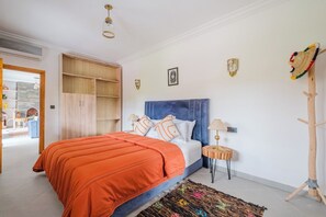 Ein Schlafzimmer mit Bett, Nachttischen, einem Kleiderschrank und Blick auf einen Außenbereich.
