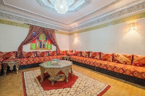 Una habitación con un sofá estampado, una mesa de centro de cristal y una alfombra decorativa.