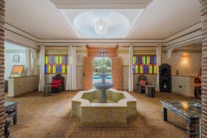 Eine Lobby mit einer Springbrunnen, Holzmöbeln und Buntglasfenstern.