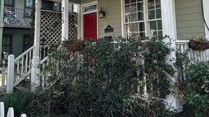 Uma casa de dois andares com varanda, porta vermelha e caixa de correio.