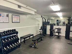 A gym with weightlifting equipment, benches, and exercise machines. - The Summit 525 (Panama City Beach)