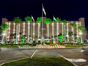 A hotel with multiple floors, palm trees, and flags. - The Summit 525 (Panama City Beach)