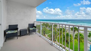 A balcony with wicker furniture, a white railing, and a view of the ocean. - The Summit 525 (Panama City Beach)