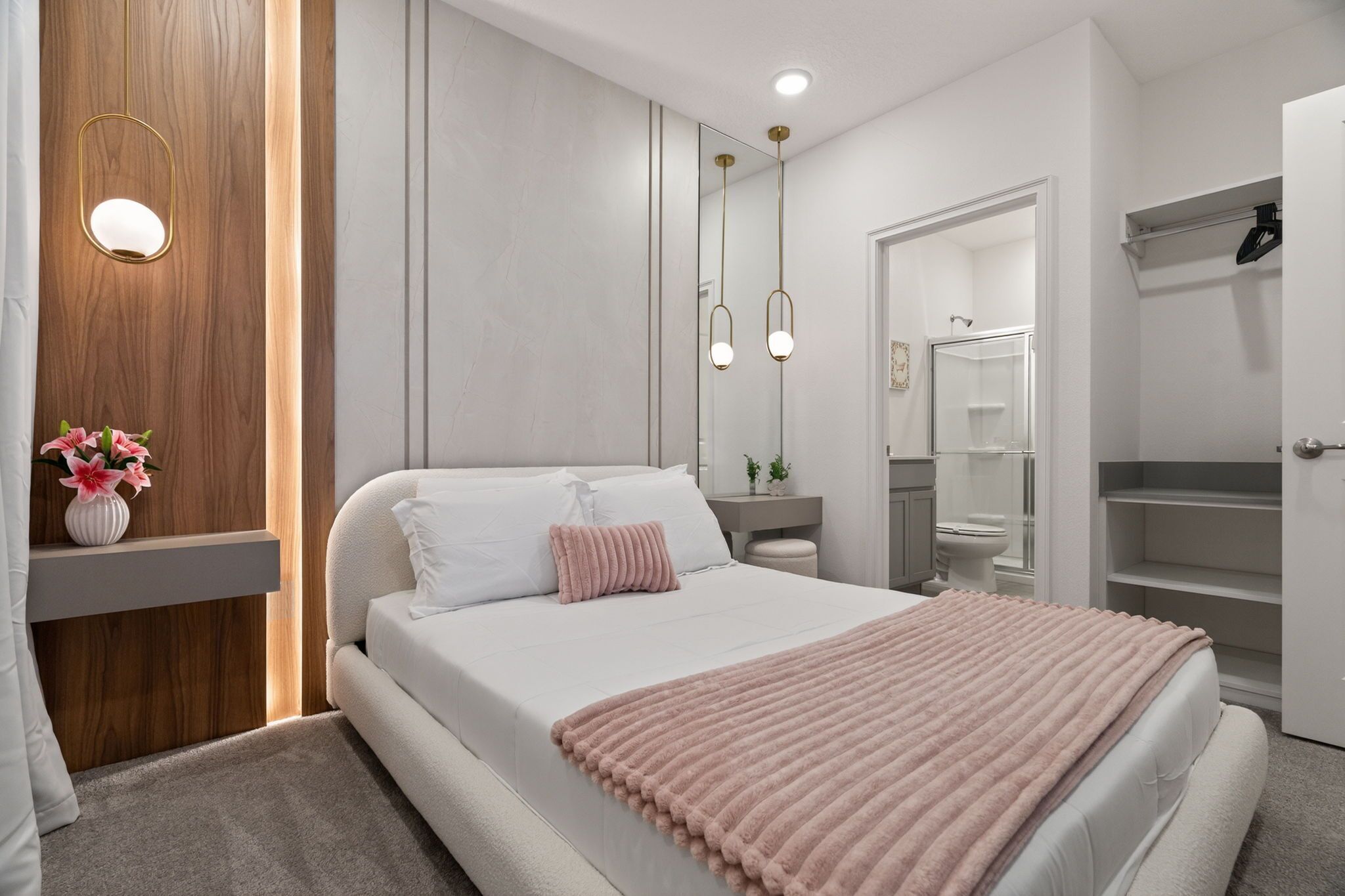 Een moderne slaapkamer met een bed, nachtkastje, spiegel en een inbouwkast.
