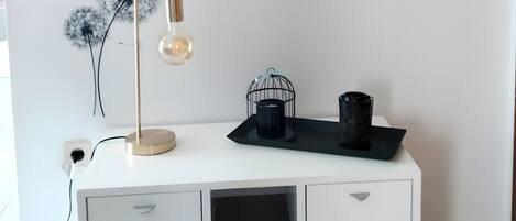 A white desk with drawers, a lamp, a black tray, and a wall decal with dandelions and the words 'Never stop dreaming.'