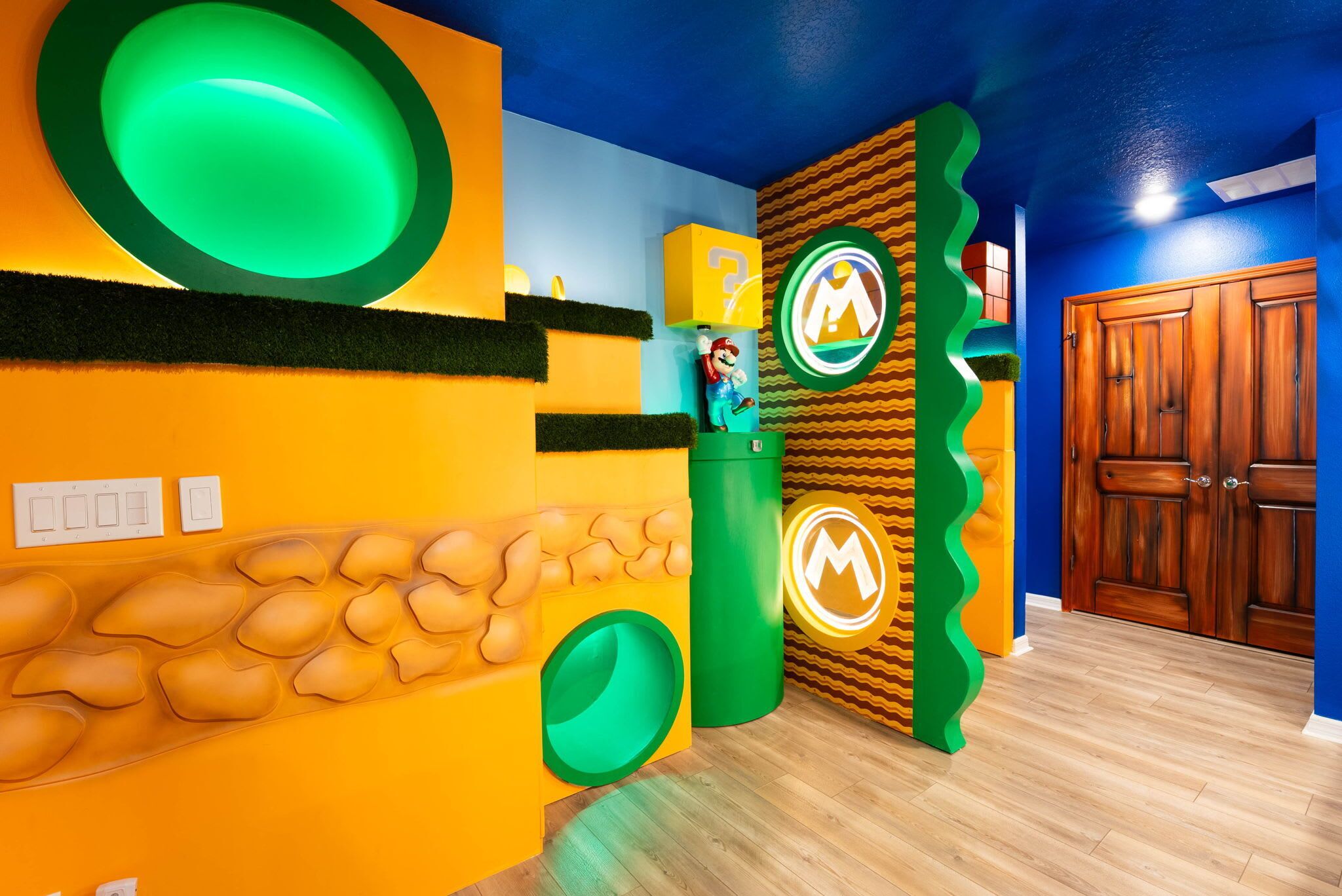 Una habitación con techo azul, puerta de madera y un diseño verde y amarillo en la pared.