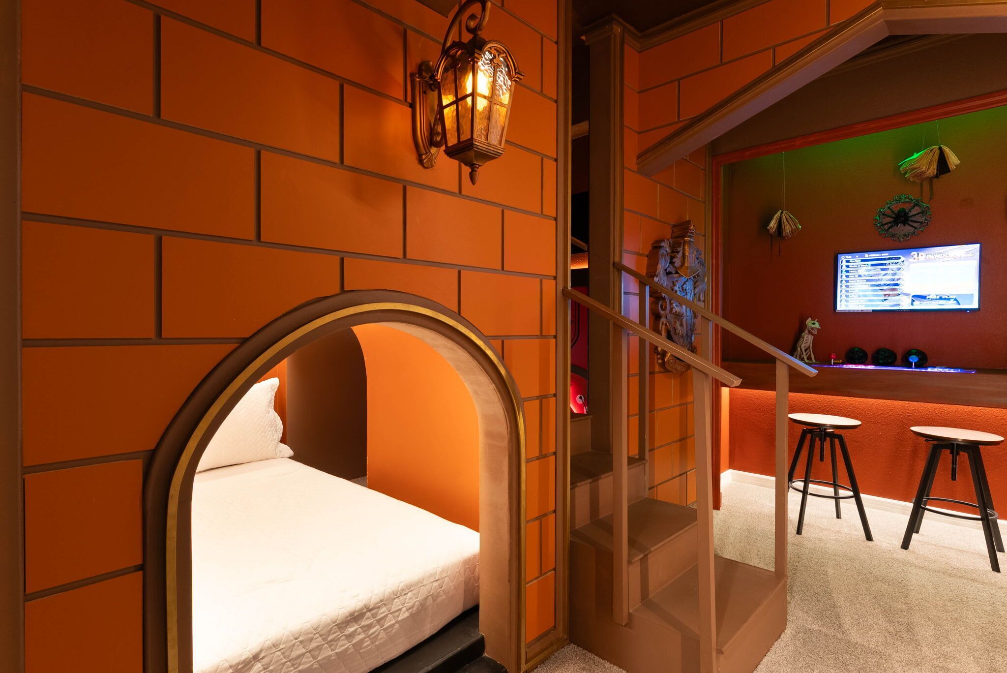 A room with a bed, a staircase, and a bar area with stools.