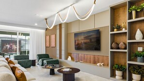 Ein modernes Wohnzimmer mit einem großen Flachbildfernseher, bequemen Sitzmöglichkeiten und dekorativen Regalen.