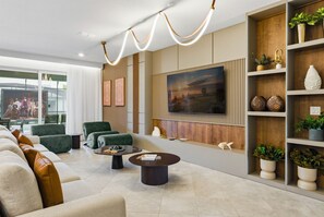 Ein modernes Wohnzimmer mit einem großen Flachbildfernseher, bequemen Sitzmöglichkeiten und dekorativen Regalen.