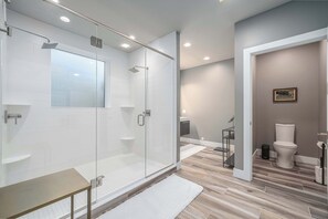 Ein modernes Badezimmer mit einer Glaskabine zur Dusche, einem weißen Waschbecken und einer Toilette.