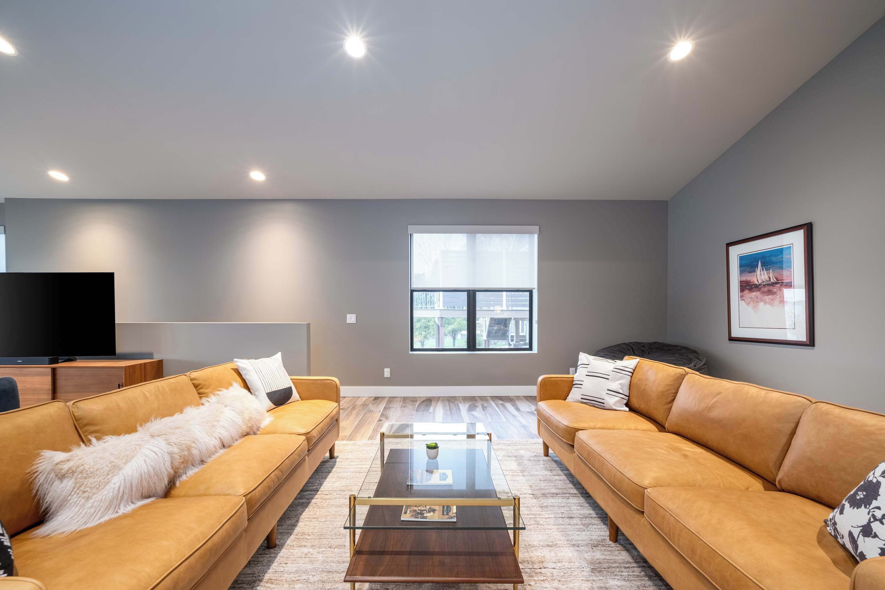 A modern living room with two sofas, a coffee table, a TV, and a large window.