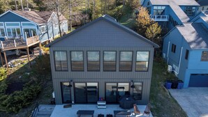 Ein modernes, zweistöckiges Haus mit überdachter Terrasse, großen Fenstern und Garage.
