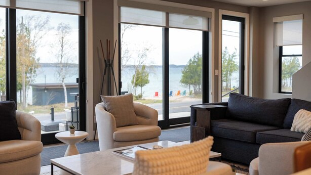 Ein großzügiger Wohnbereich mit Seeblick, ausgestattet mit einer Couch, Sesseln und einem Couchtisch.