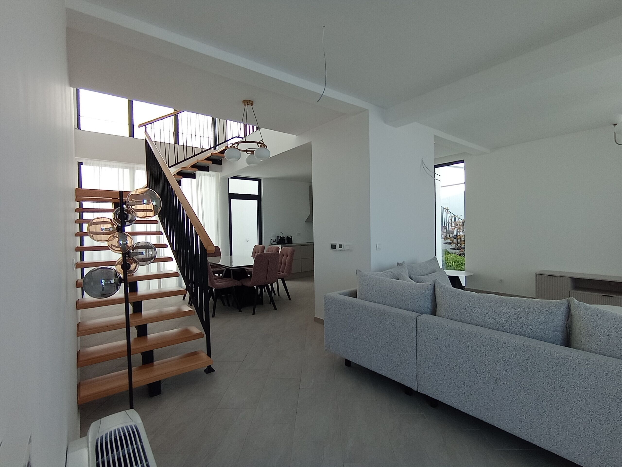 Un intérieur moderne comprenant un escalier, un coin repas et un salon avec un canapé.