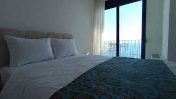 Une chambre d’hôtel avec un lit, une fenêtre donnant sur un beau paysage et un balcon.