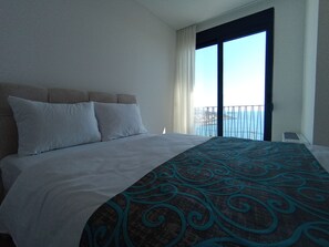 Una habitación de hotel con cama, ventana con vistas y balcón.
