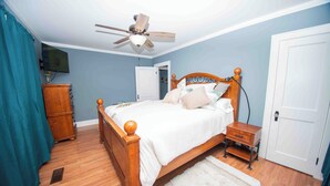 A bedroom with a wooden bed, a ceiling fan, a nightstand, a dresser, and a white rug. - Welcome to the Honey House in beautiful Hampton South Carolina (Hampton)