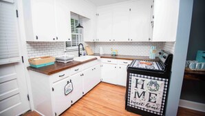 A kitchen with white cabinets, a wooden countertop, a sink, and a refrigerator with a home-themed cover. - Welcome to the Honey House in beautiful Hampton South Carolina (Hampton)