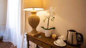A wooden table with a lamp, a potted orchid, teacups, a teapot, and a box of tea. - Dimora Sinibaldi (Palermo)