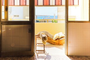 Ein Zimmer mit Meerblick, einem Ventilator und einem Sessel.