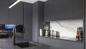 Une cuisine moderne avec un robinet élégant, un pare-feu en marbre et un téléviseur à écran plat en arrière-plan.