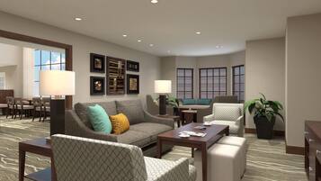 A hotel lobby with a sofa set, armchairs, a dining area, and a large window with blinds.