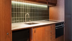 A kitchen with wooden cabinets, a stainless steel sink, and a tiled backsplash. - Adina Hobart (Hobart)
