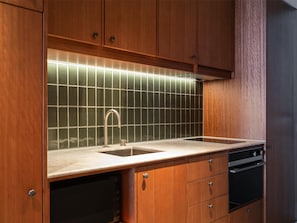 A kitchen with wooden cabinets, a stainless steel sink, and a tiled backsplash. - Adina Hobart (Hobart)