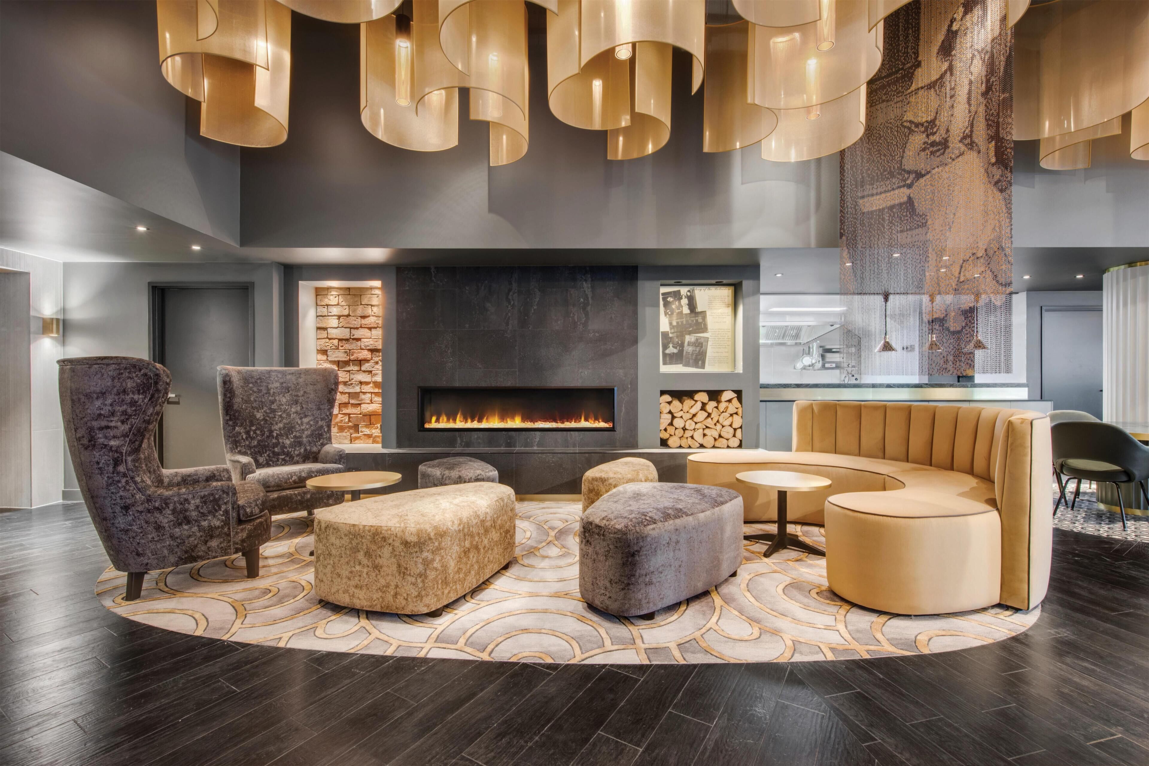 A modern lounge with a fireplace, seating, and pendant lighting.