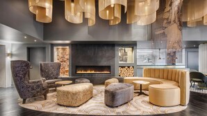 A modern lounge with a fireplace, seating, and pendant lighting. - Adina Hobart (Hobart)