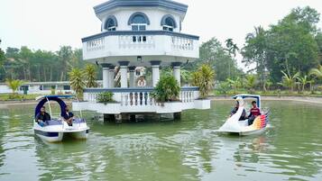 Duas embarcações em forma de cisne em águas calmas, com uma estrutura de pavilhão central.