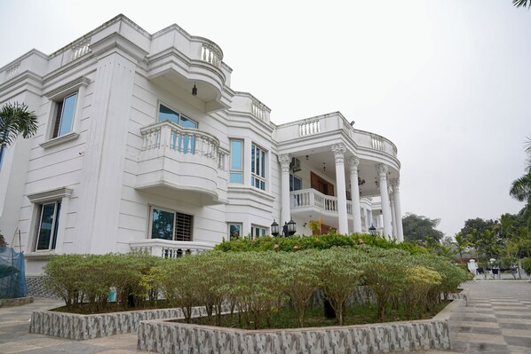 A white building with multiple balconies and a central courtyard with plants.