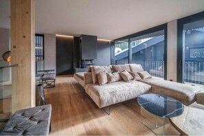 Una sala de estar moderna con un sofá, una mesa de centro de vidrio y un comedor con un banco.