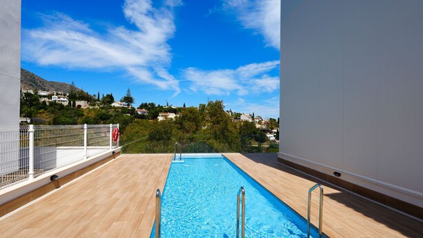 A rooftop swimming pool with a view of a hillside town. - Pine Hills - New Apartment Fuengirola (Fuengirola)