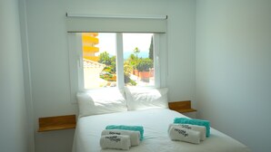 A hotel room with a bed, pillows, and a window with a view. - Pine Hills - New Apartment Fuengirola (Fuengirola)