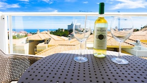 A balcony with a table, a bottle of wine, and two glasses. - Pine Hills - New Apartment Fuengirola (Fuengirola)